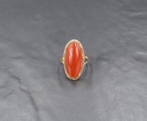 A carnelian cabochon ring, the oval carnelian in a bezel setting with rope detail, having pierced