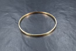 A yellow metal bangle, marked 9ct of plain design, approximately 20cm inner circumference, 11.3g
