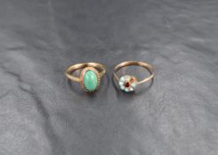 Two yellow metal rings, comprising one turquoise and garnet daisy style ring, and a green cabochon