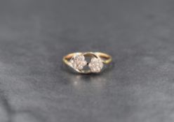 A floral diamond ring having two seven diamond set flower motifs with crossover shoulders on a