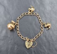 A 9ct gold charm bracelet having three 9ct gold and yellow metal charms and a padlock clasp,