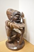 A large African carved tribal study modelled as a warrior brandishing a spear and staff, raised on a