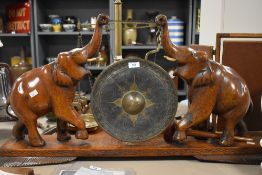 A late 19th century Indian carved wood and painted brass table gong, formed as two elephants with
