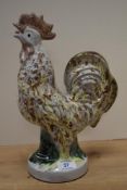 A 20th Century Continental hollow cast cockerel study, drip glazed in shades of yellow, brown, and