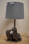 A contemporary table lamp incorporating a pair of otters in silvered finish.