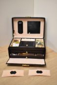 A black faux leather jewellery box with gold colour hardware, containing a selection of costume