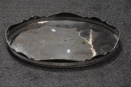 An Edwardian silver plated serving tray, of oval form with galleried edge and raised on four moulded
