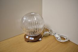 An Art Deco style table lamp, having spherical cut glass shade and raised on a footed oak base,