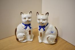 A pair of 19th Century Staffordshire cats, with blue ribbons, yellow and black painted eyes, black