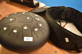 A steel tongue drum (C) and carry case with beaters and instructions