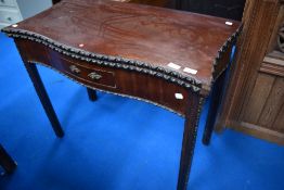 A late 19th or early 20th Century mahogany fold over tea table having shaped and carved edge,