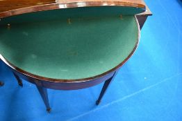 A 19th Century mahogany fold over card table of demi lune form having line inlay , on square tapered