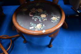 An early 20th Century circular coffee table having woolwork top under glass