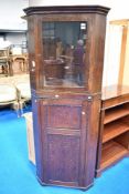 A period oak corner cupboard having glazed top section with enclosed paneled lower section, height