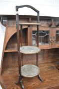 An early 20th Century oak framed cake stand with brass platforms