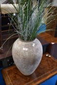 A reproduction urn with imitation grass and silvered twigs
