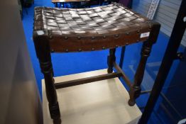 An Arts and Crafts style leather lattice top stool on dark oak frame