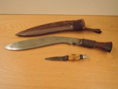 A Gurkha Kukri Knife with curved single edge blade and horn hilt in leather scabbard, one small