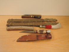 A pair of Metal Straps for a Tunic, two empty Shells, Sheaf Knife and a Red & White Plume