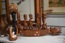 An African carved hardwood bust and an oriental carved and inlaid boat, depicted with rowing figures
