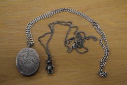A large silver locket with foliate motif decoration, with multiple frames on a silver curb link