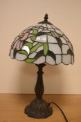 A Tiffany style glass table lamp with domed shade and raised on a moulded Art Nouveau style base,