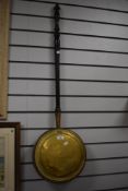 A Victorian brass warming pan with ebonised turned wood handle, 102cm long
