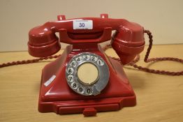 An early 20th Century red bakelite rotary dial telephone