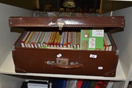 A brown leather suitcase containing sporting related books including 'Double International', 'The
