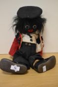 An early 20th Century soft bodied golly doll, with stitched facial features and wearing beefeater