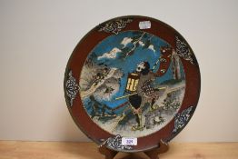 A Japanese cloisonné enamel plate, of shallow dished circular form, decorated with warriors and