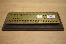 A brass cribbage board, inscribed 'R.Newsham' to the brass plate, and mounted upon a moulded wood