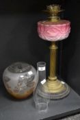 A Victorian oil lamp, having a moulded pink opaline glass reservoir above a twisted brass column,