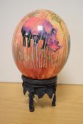 A decorative blown ostrich egg, transfer printed with lion, elephant and rhino and over painted with
