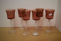 A set of six 20th Century Bohemian ruby coloured glass wine glasses, having gilt etched foliate