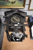 An early 20th Century Black Forest cuckoo clock, heavily carved and surmounted by a bird and flowers