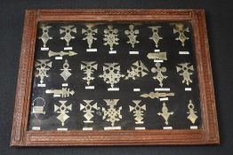 A framed collection of white metal Tuareg Crosses, each representing a village or region in Niger,