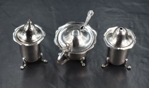 A George V silver three-piece condiment set, having lobed rims and raised on three cabriole legs,