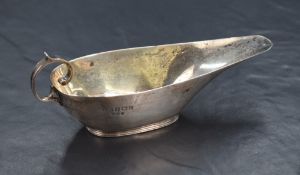 A George V silver sauce boat of narrow elongated form, having a shallow spout opposed by a scroll