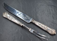 An Elizabeth II silver handled carving set, comprising a fork and knife having embossed scroll