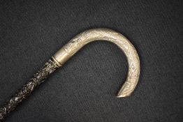 A Chinese export silver mounted walking stick, the dark wood cane having decorative relief Cantonese