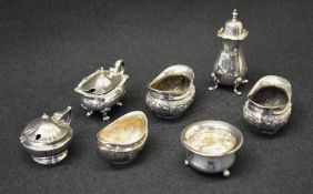 A assortment of silver mustards, salts and a pepperette, of various design including embossed floral