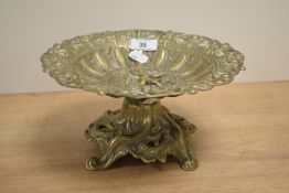 A cast brass pedestal dish, cast with various repeating motifs and central figure, raised on a