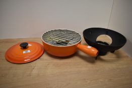 A vintage Le Creuset orange cast fondue set.