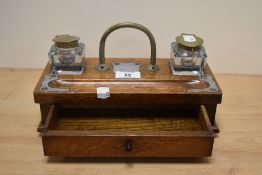 A late 19th/early 20th century oak inkstand, of oblong for, with arched brass handle, two clear