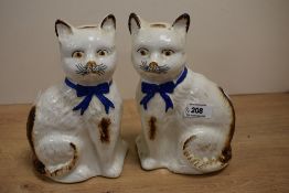 A pair of 19th Century Staffordshire cats, with blue ribbons, yellow and black painted eyes, black
