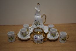 A continental porcelain liqueur set, comprising decanter, six 'cups' and crescent form stand, each