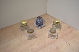 Four glass ink wells with brass tops and one without.