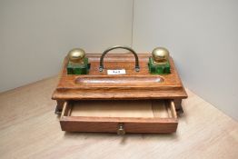 An oak desk tidy with two green glass ink wells and drawer
