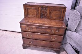 A 19th Century oak chest of drawers having upper cupboard section with central carved panel, over